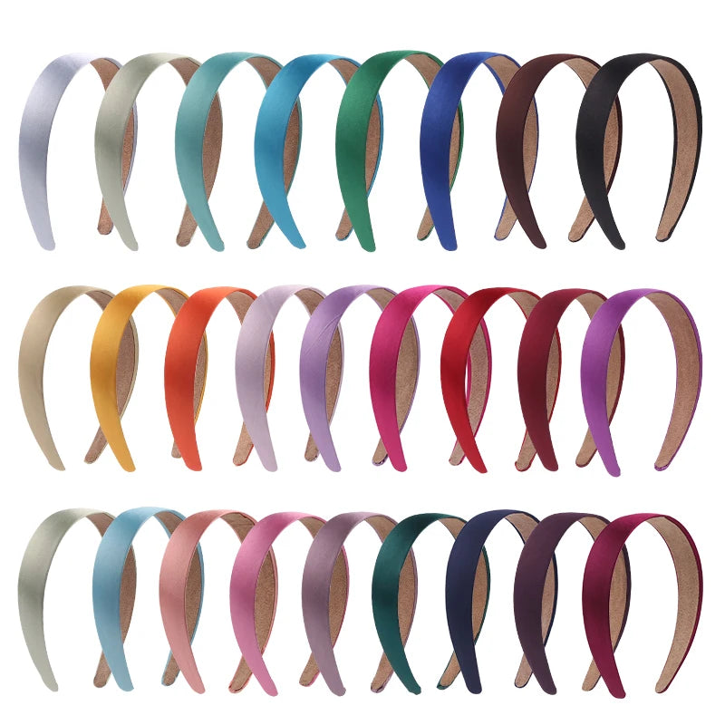 A collection of solid satin hair bands in various shades of green, blue, pink, and brown.