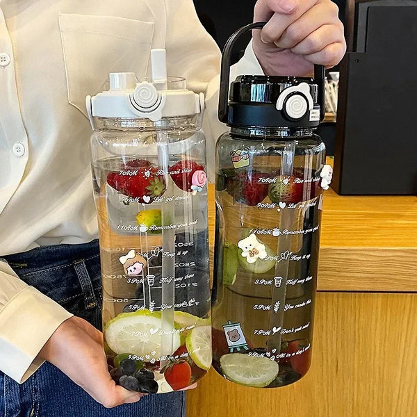 A clear glass water bottle filled with amber liquid and various fruits, held by a person.