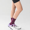 A person wearing purple socks and black leggings is shown in a side view.