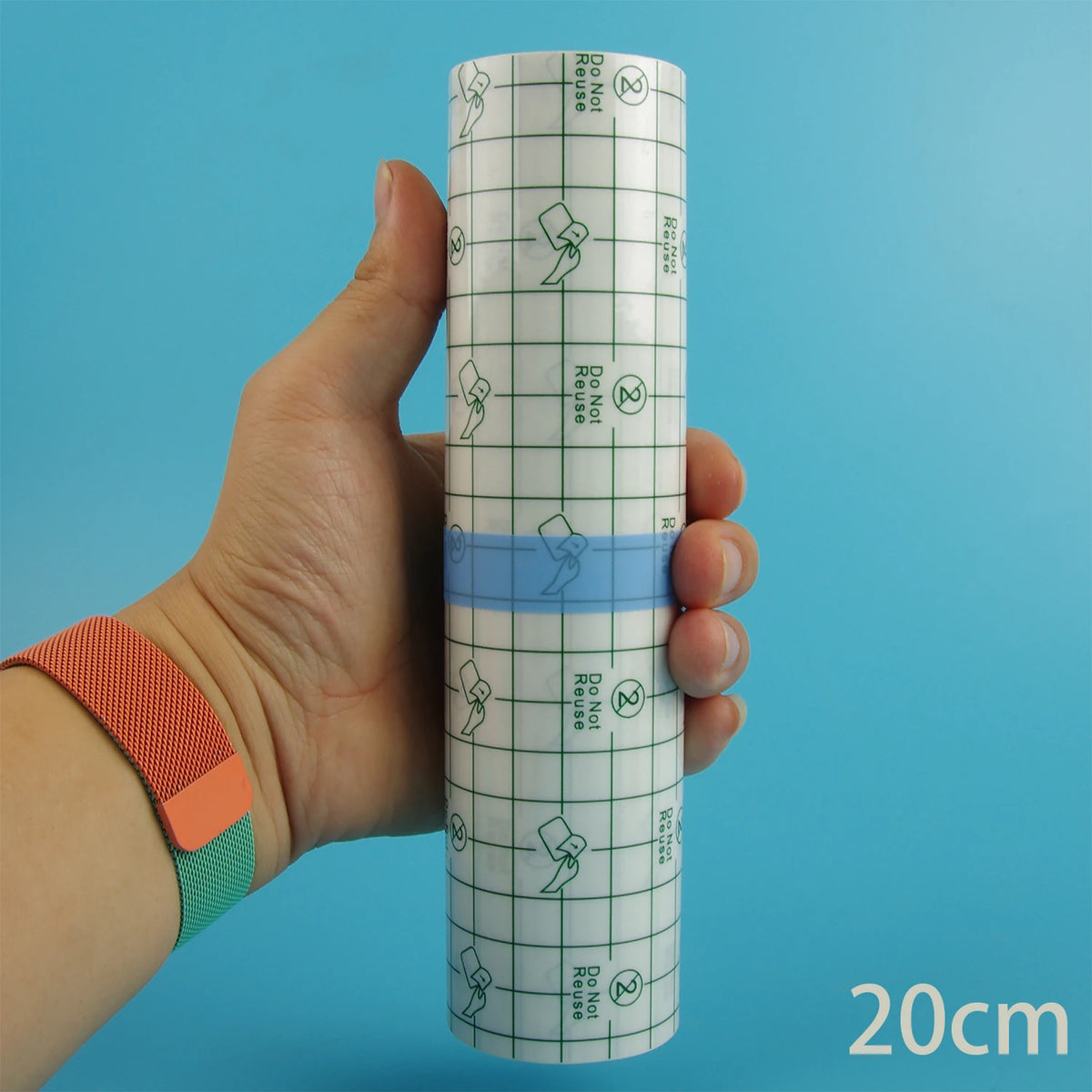 Eine Hand hält eine Rolle wasserfeste Tattoo-Heilfolie mit Gittermuster und blauer Klebeband auf blauem Hintergrund.
