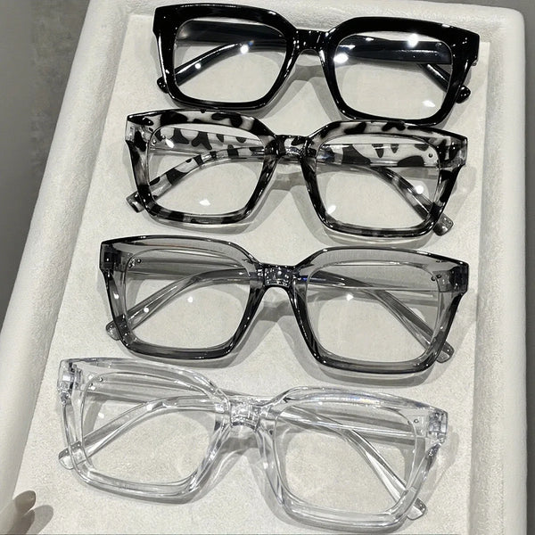 Une collection de cinq lunettes carrées anti-lumière bleue présentées dans une boîte blanche.