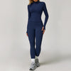 A woman wearing a navy blue long-sleeved yoga sports set consisting of a top and leggings.