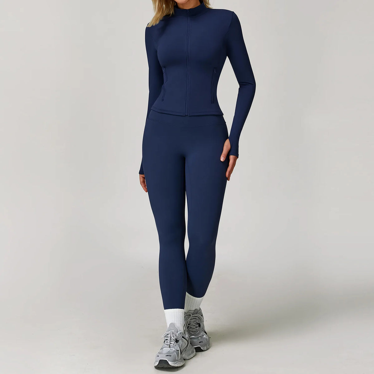 A woman wearing a navy blue long-sleeved yoga sports set consisting of a top and leggings.