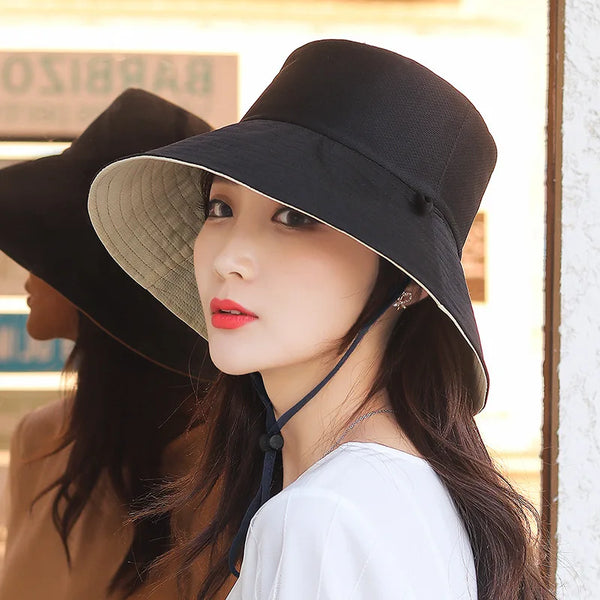 A woman wearing a black double-sided wide brim bucket hat with a light beige lining and red lipstick.