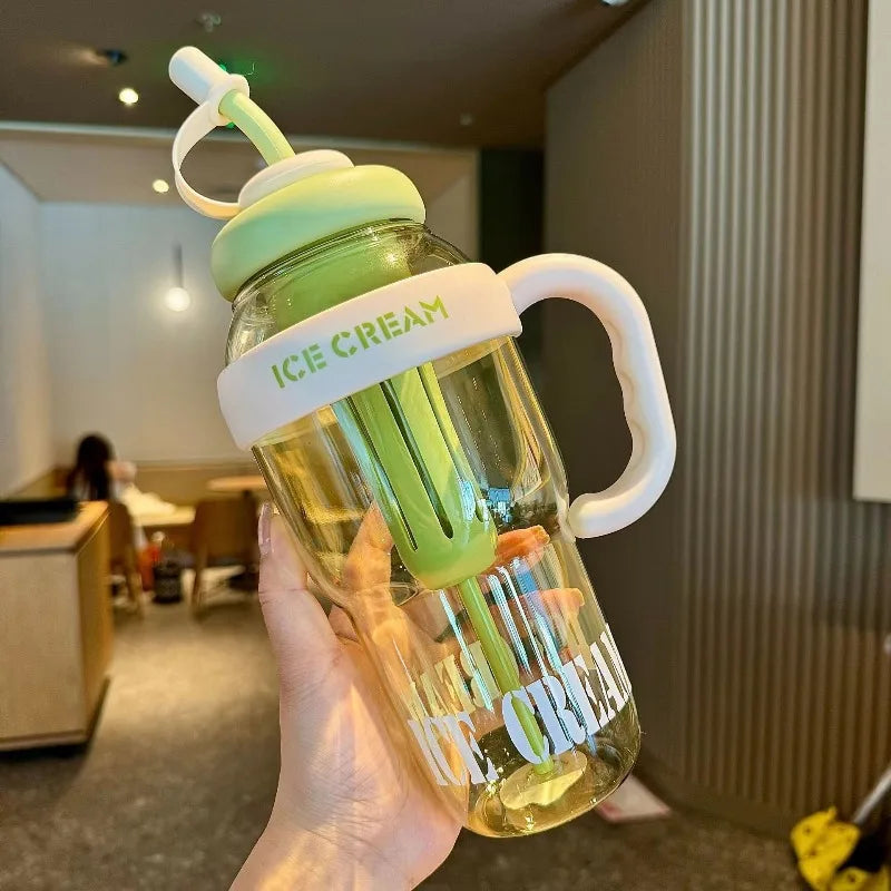 A hand holds a clear plastic sports water bottle with a lime green straw and lid, labeled Ice Cream.