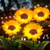 Three bright orange yellow solar sunflower LED stake lights blooming on green foliage.