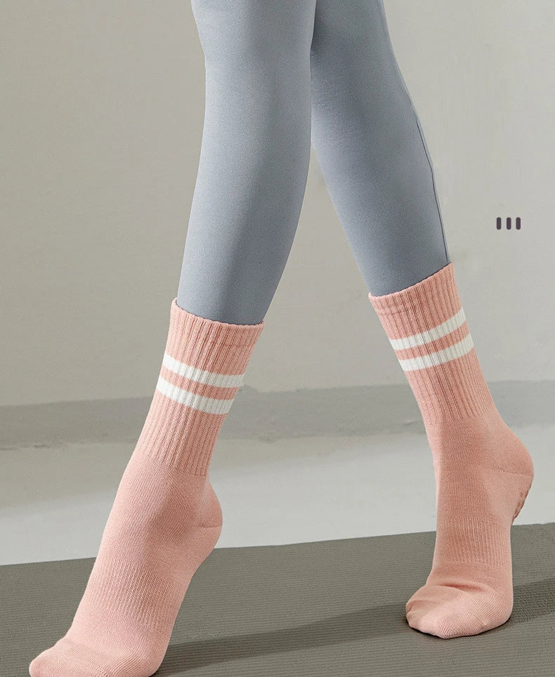 Un par de calcetines de yoga y pilates de punto rosa antideslizantes puestos en las piernas.