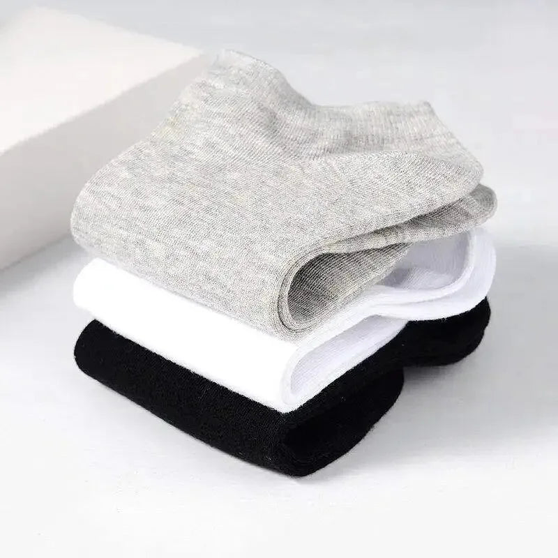 Pila de calcetines de algodón unisex transpirables en gris, blanco y negro.