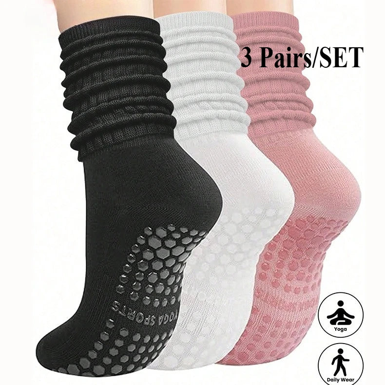 A set of three pairs of black, white, and pink silicone Pilates and yoga socks shown vertically.