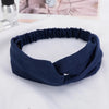 A navy blue fabric headband or hair accessory is shown lying on a white surface.