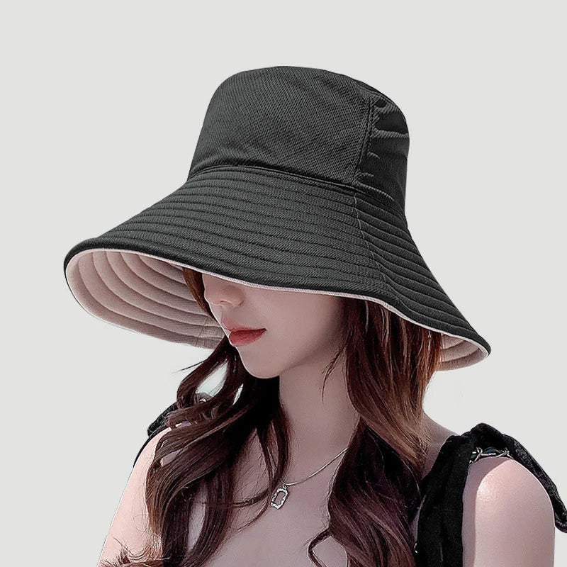A woman wearing a dark gray double-sided wide brim bucket hat for sun protection.