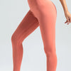 A model wearing seamless high-waist yoga leggings in coral pink and white sneakers.