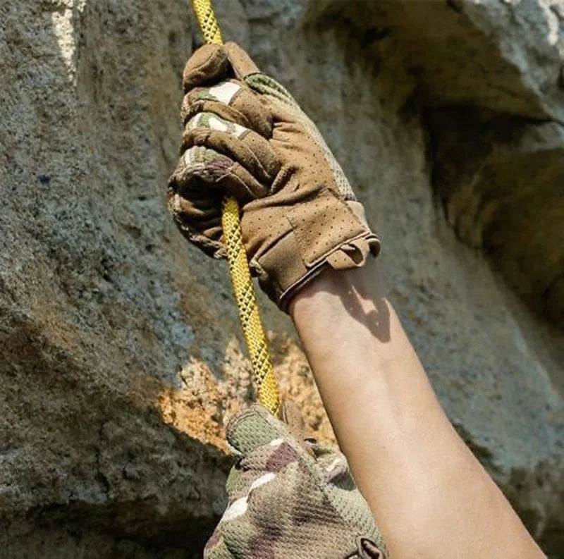 Une main portant des gants sport tactiques agrippe une corde jaune sur un fond rocheux.