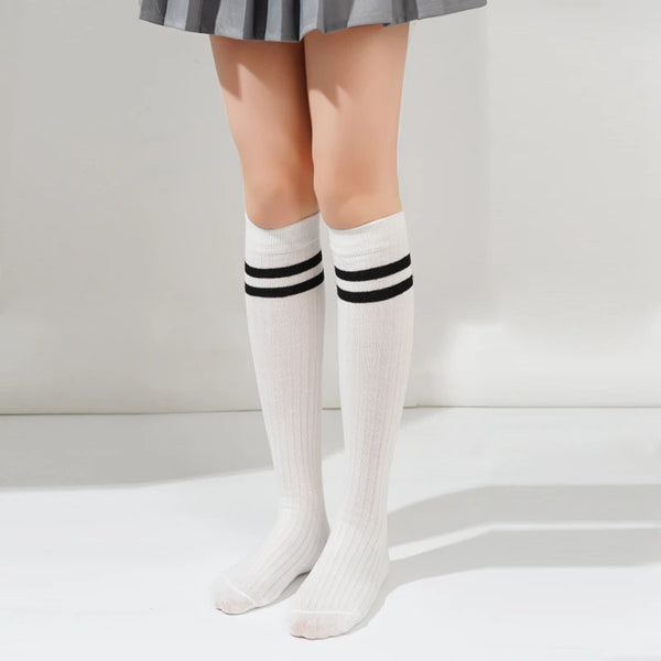 White cotton knee high socks with black stripes worn by a person.