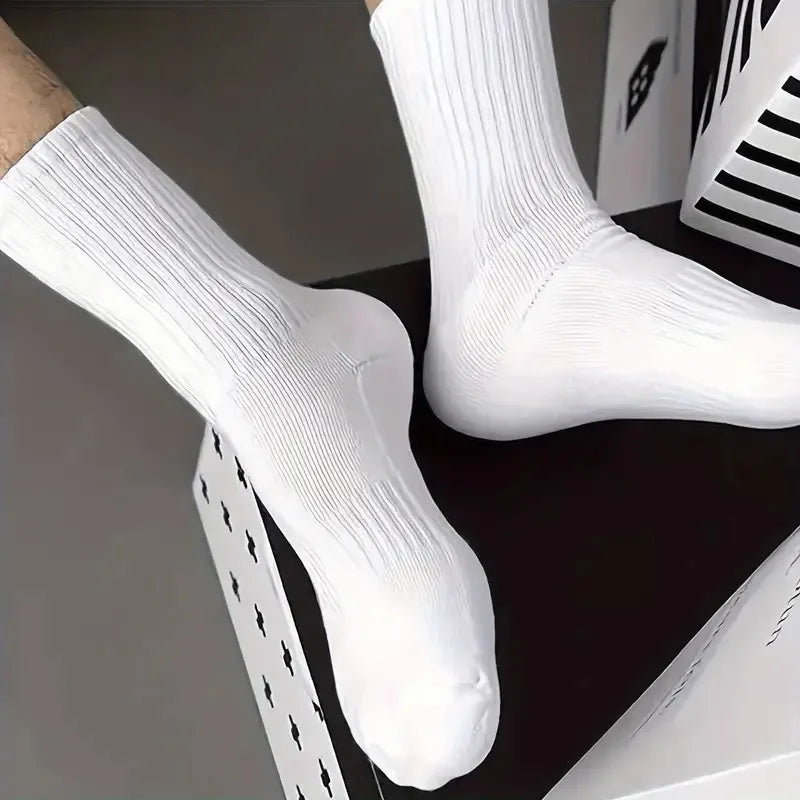Une paire de chaussettes tubulaires tricotées blanches sur une surface sombre.