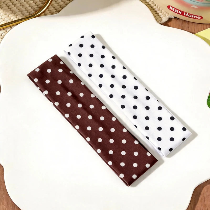 Eine braune und eine weiße Polka-Dot-Stoff-Haarband werden auf einer weißen Oberfläche präsentiert.
