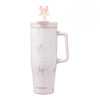A pink insulated thermos mug with white pearl inlay decoration and a decorative ribbon top.