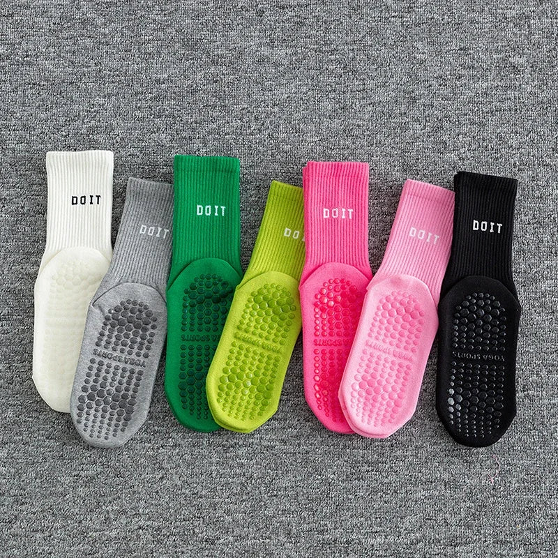 Eine Sammlung von acht Paar farbenfroher, atmungsaktiver, rutschfester Yoga- und Fitnesssocken auf einer grauen strukturierte