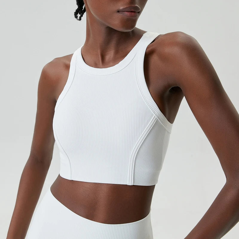 A model wearing a white ribbed high-impact stretch yoga crop top and matching bottoms.