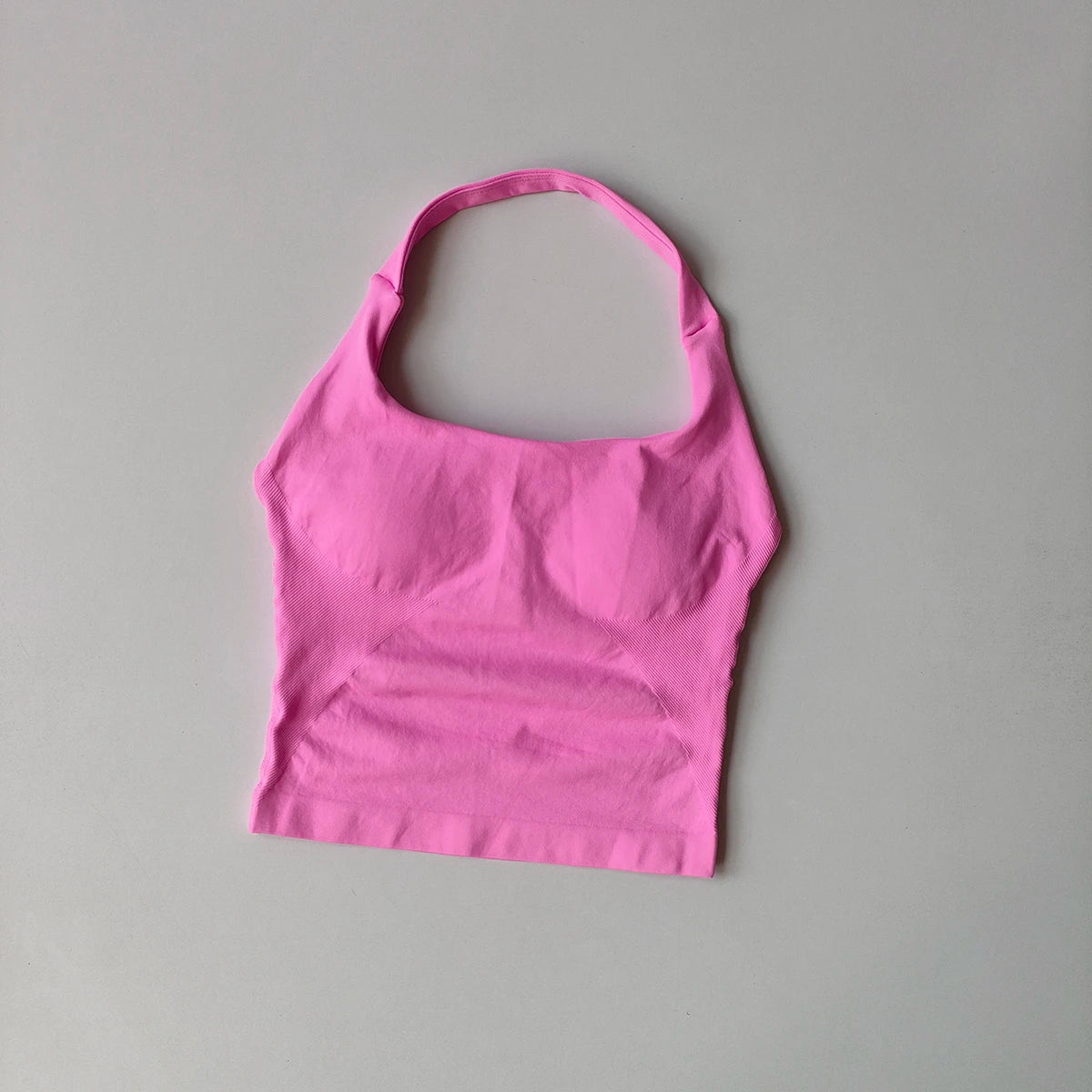 Haut sans coutures rose vif pour femmes, col halter, pour yoga et fitness, sur fond gris clair.