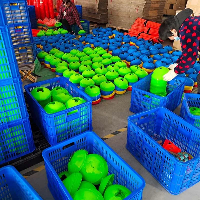A variety of green and blue soccer training discs are displayed in plastic crates and baskets.
