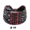 A close-up of a patterned fabric headband featuring floral and geometric designs in shades of pink, blue, and black.