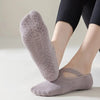 A close-up of a pair of grey non-slip yoga and gym socks with silicone grip worn on a person's foot.