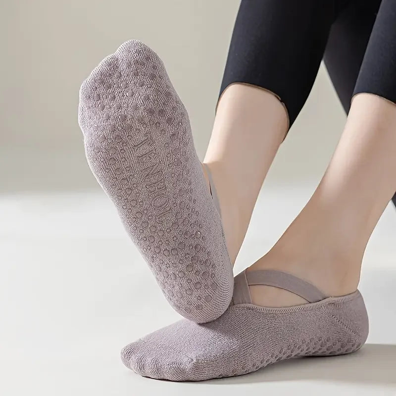 A close-up of a pair of grey non-slip yoga and gym socks with silicone grip worn on a person's foot.