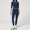 A woman wearing a navy blue yoga and fitness leggings set with a matching long-sleeved top.