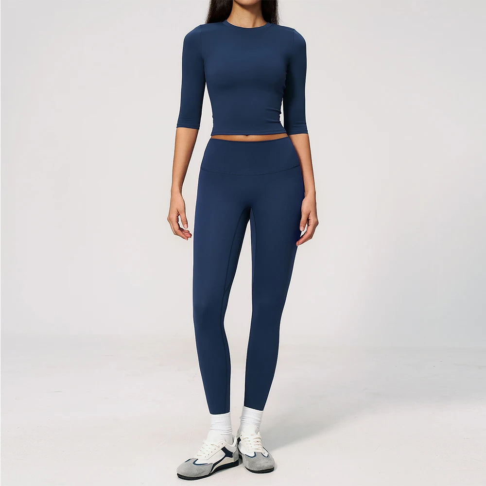 A woman wearing a navy blue yoga and fitness leggings set with a matching long-sleeved top.
