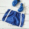 Un par de llaveros de guantes de boxeo azules sobre tela blanca y pantalones cortos deportivos azules.