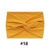 A mustard yellow fabric headband folded into a crisscross design.