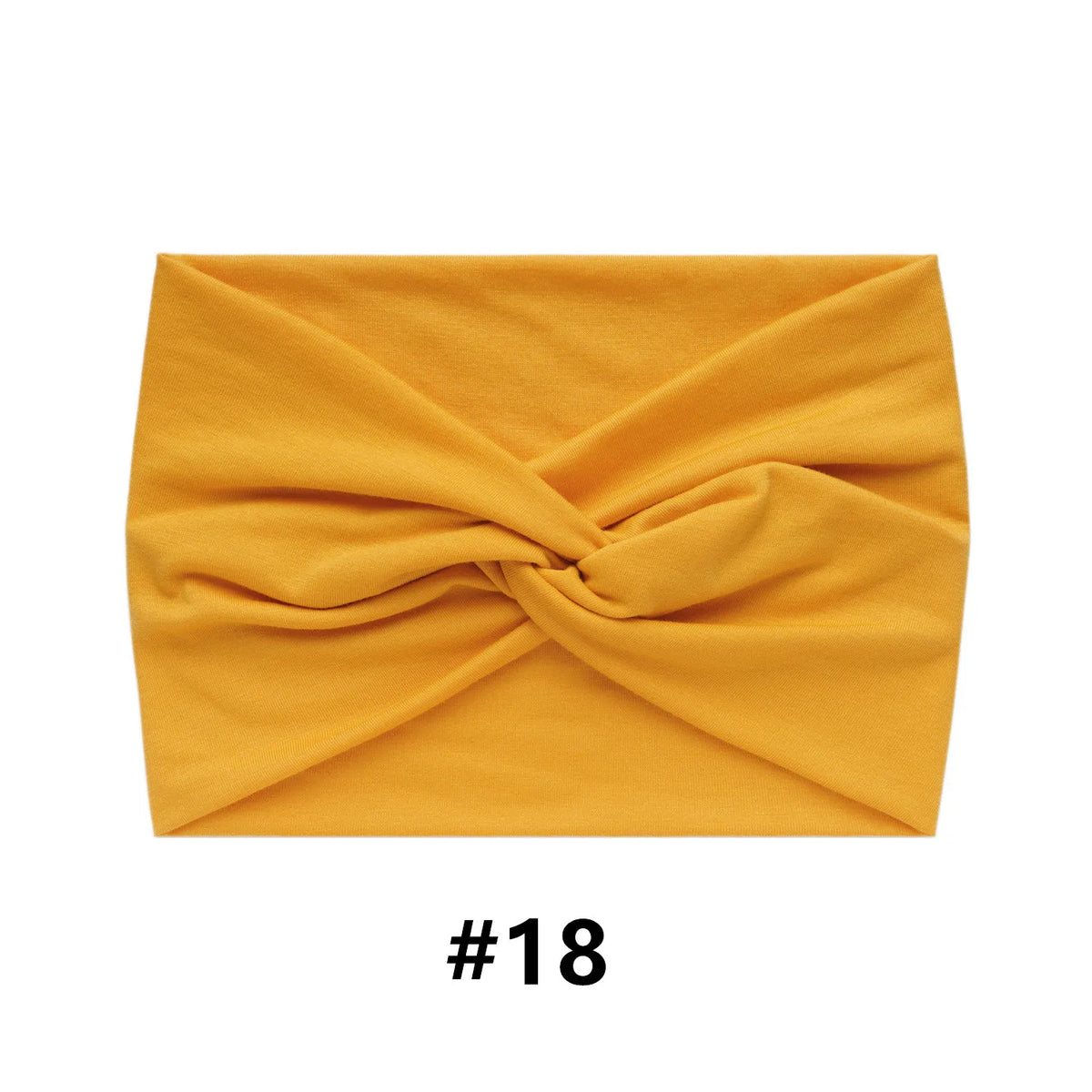 A mustard yellow fabric headband folded into a crisscross design.