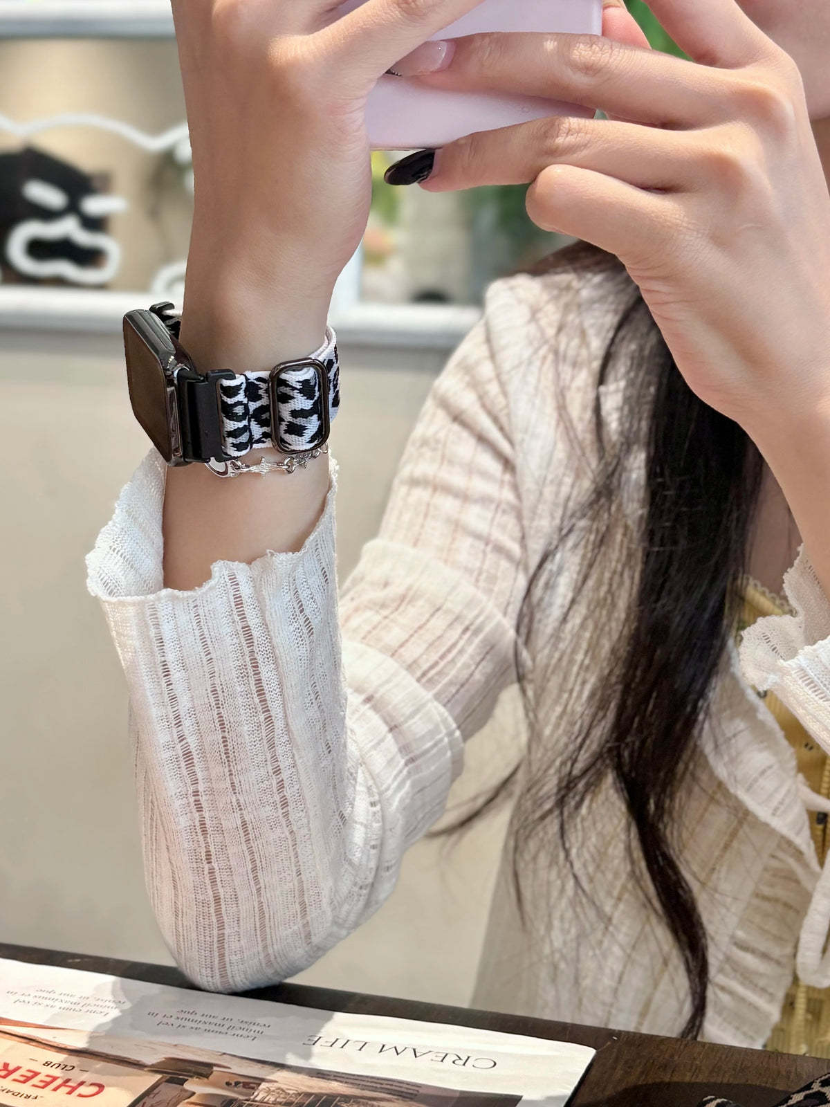 A close-up of a hand wearing a black and white leopard print silicone watch band on a wrist.
