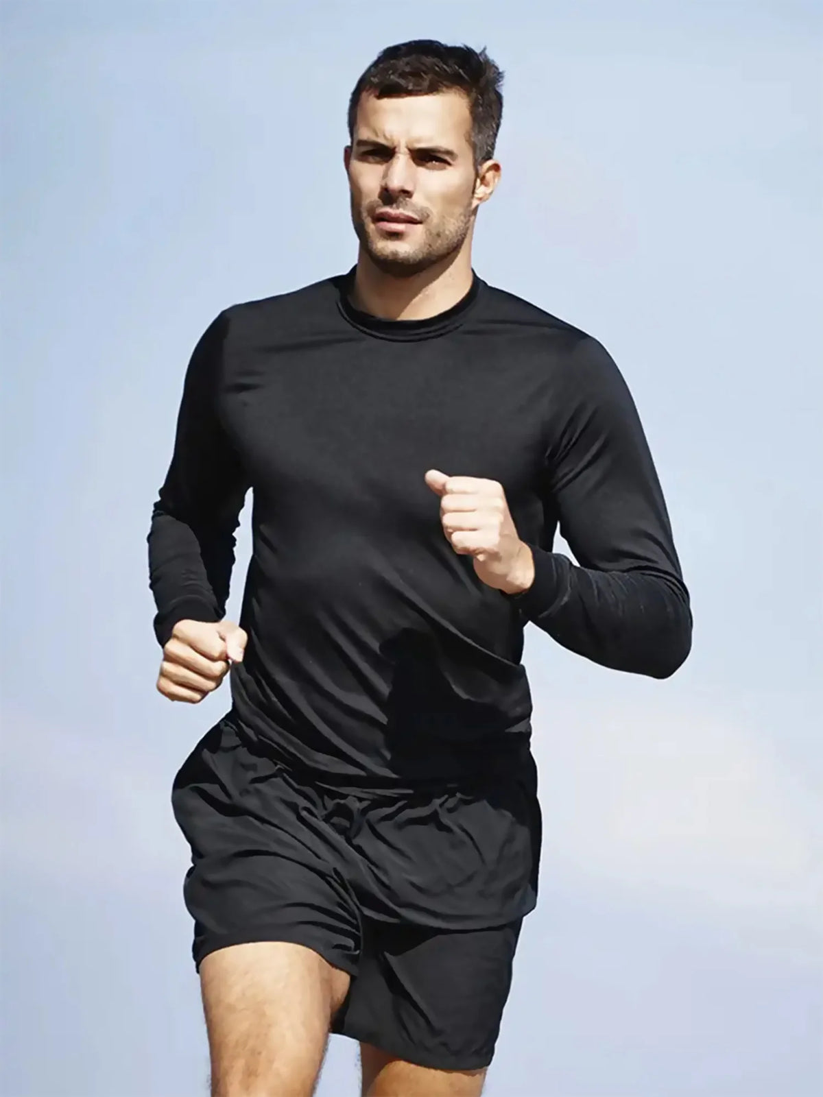 A male model wearing a black performance quick-dry long-sleeve shirt and shorts, posing outdoors.