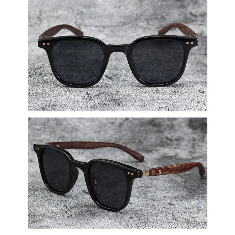 A pair of black sunglasses with brown wood grain frames and polarized lenses resting on a gray textured surface.