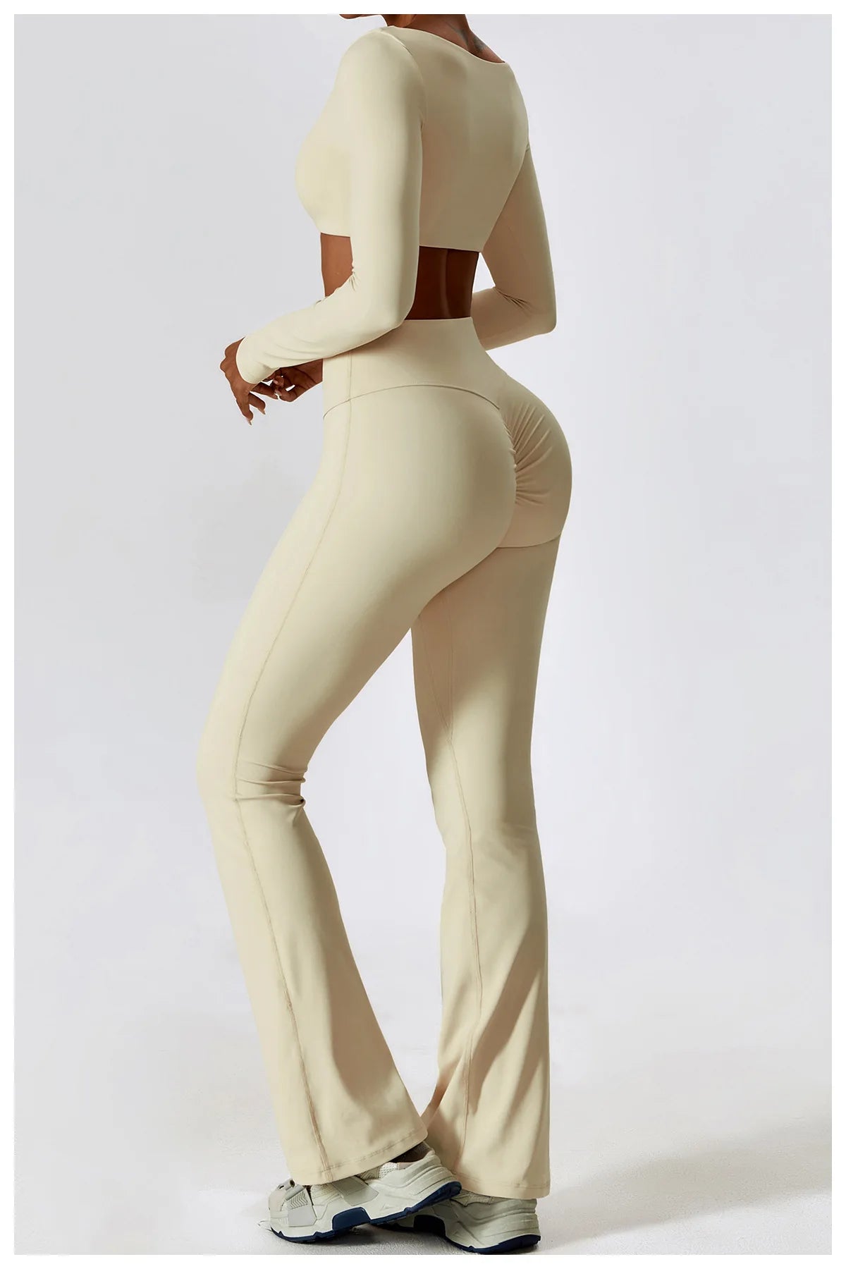 A woman models a beige women's performance tracksuit set featuring a cropped top and high-waisted pants.