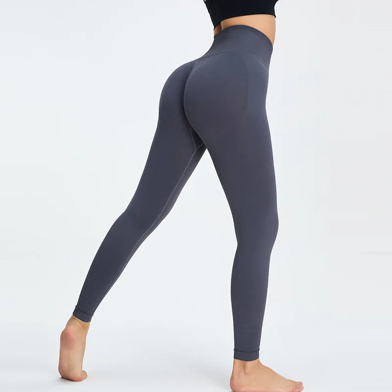 A model wearing dark gray high-waist seamless yoga leggings and a black top, shown in a side view.