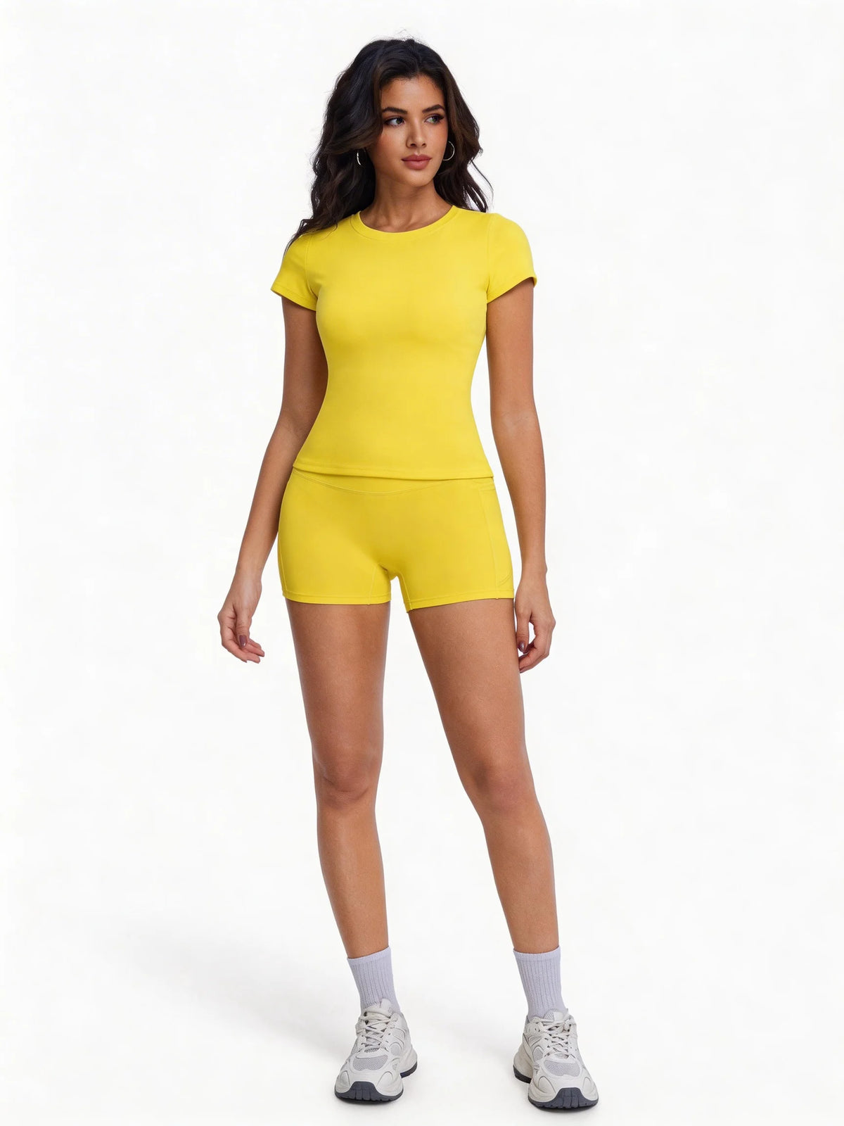 A woman models a yellow two-piece workout set consisting of a short-sleeved top and matching shorts.