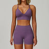 Eine Frau modelliert ein nahtloses lila Sport-Yoga-Set mit Crop-Top und enganliegenden Shorts.