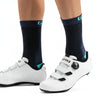 A pair of white cycling shoes and dark blue socks with teal accents are shown from the side.