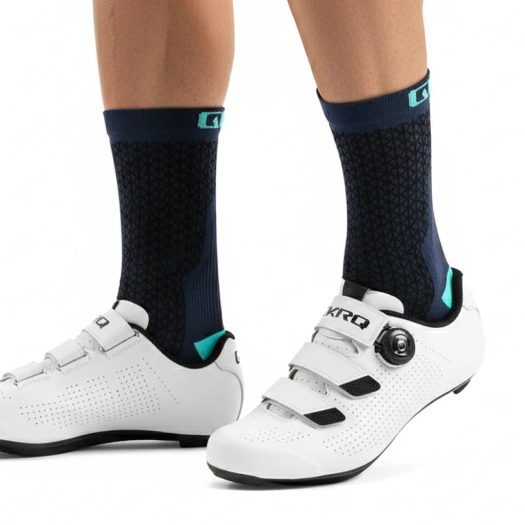 A pair of white cycling shoes and dark blue socks with teal accents are shown from the side.