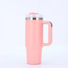 Tasse isotherme en acier inoxydable rose avec couvercle argenté et poignée noire.
