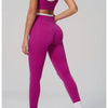 Eine Frau modelliert ein magentafarbenes Yoga- und Sportanzug-Set mit Crop-Top und Leggings.