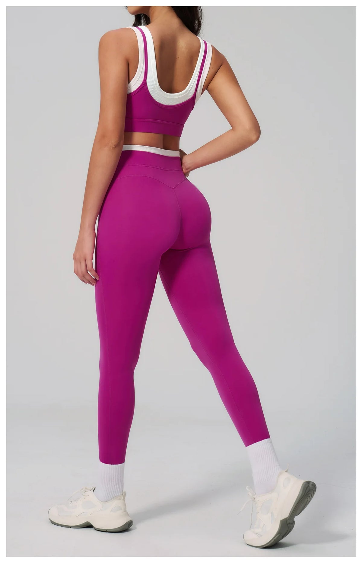 Eine Frau modelliert ein magentafarbenes Yoga- und Sportanzug-Set mit Crop-Top und Leggings.