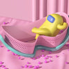 A yellow swimming goggle for a child rests in a pink plastic container on a pink fabric.