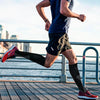 A person running outdoors wearing black compression socks and athletic clothing.