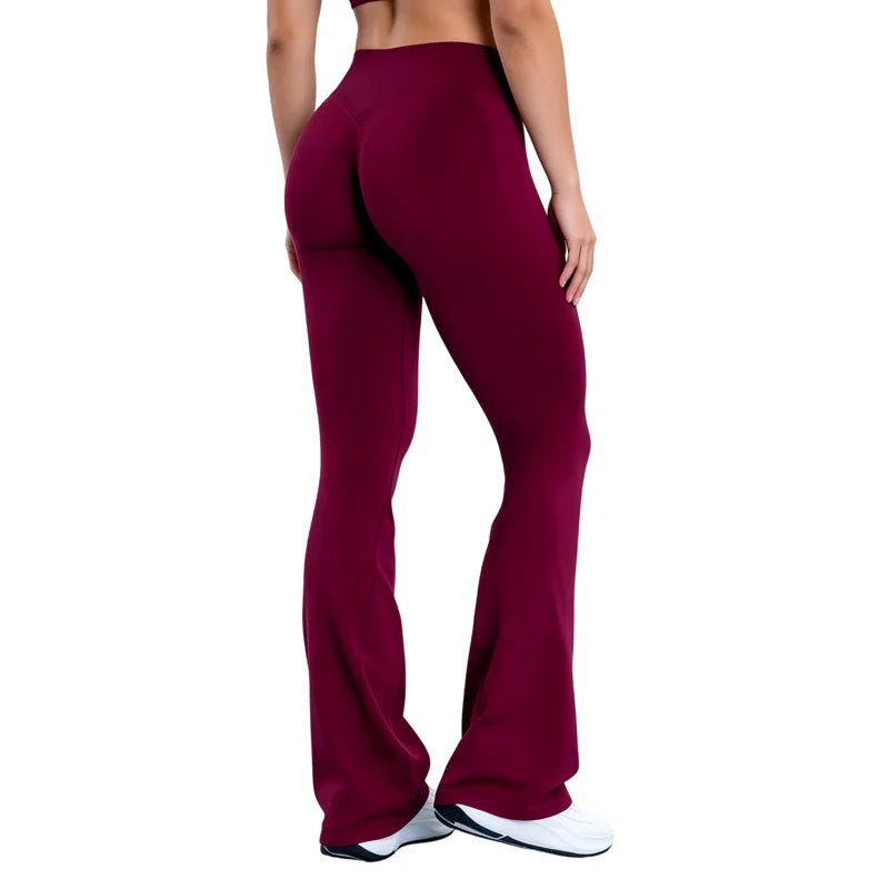 A model wearing deep burgundy seamless flared yoga leggings and white athletic shoes.