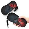 A black pouch featuring a red and black spider web design is being held by a hand.