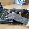 Eine Person tippt auf einem Laptop mit grauen Kompressionshandschuhen für die Handgelenke.